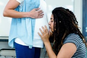 birth partner kissing pregnant partner's belly