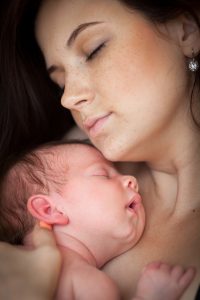 Young parent skin to skin with newborn
