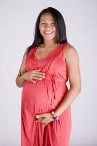 Pregnant woman in red dress holding belly