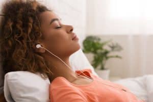 Person in bed sleeping with earbuds