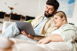 Couple sitting on sofa looking at Hypnobabies course on a laptop